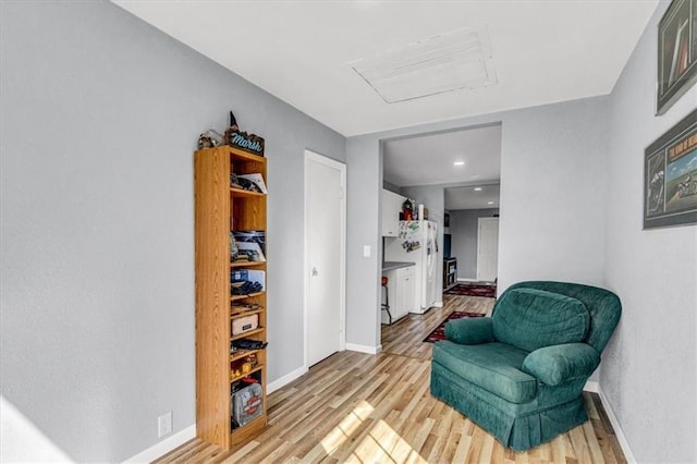 sitting room with attic access, baseboards, and light wood-type flooring