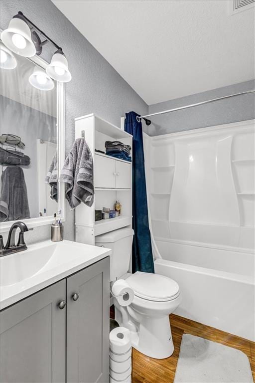 bathroom featuring toilet, shower / tub combo with curtain, wood finished floors, a textured wall, and vanity