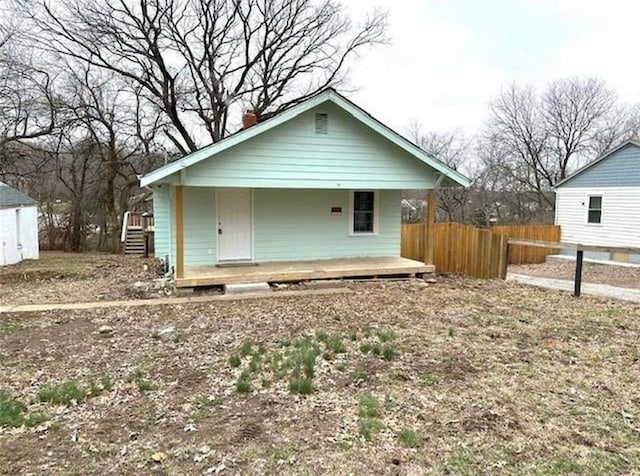 view of front of house featuring a porch, fence, and a chimney