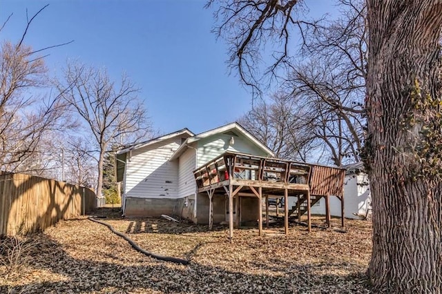 rear view of property with stairway, a deck, and fence