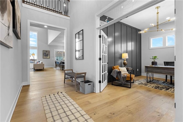 interior space with plenty of natural light, a towering ceiling, and wood finished floors