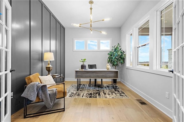 office area with light wood-type flooring, visible vents, baseboards, and a chandelier