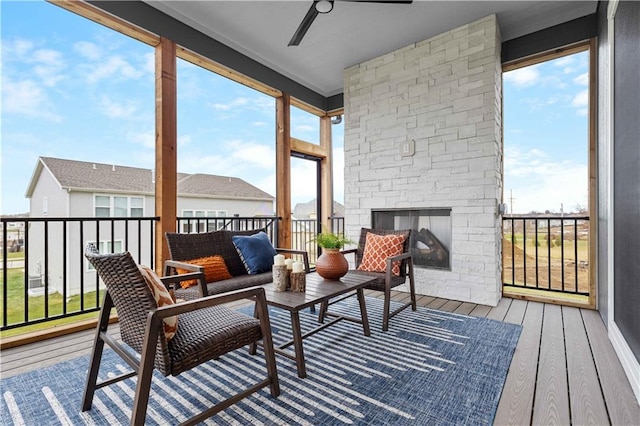 sunroom featuring an outdoor stone fireplace and ceiling fan