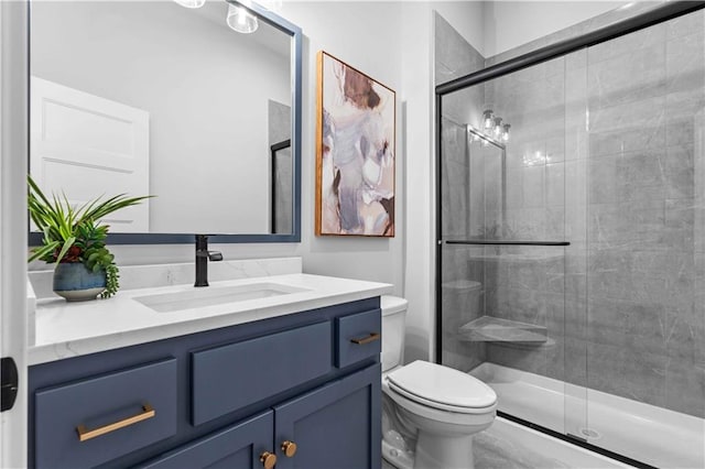 full bathroom featuring a stall shower, toilet, and vanity