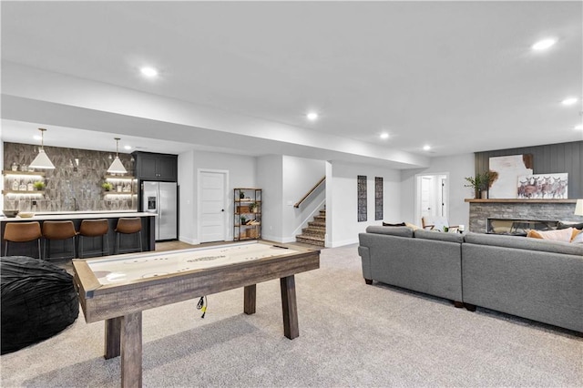 game room with recessed lighting, baseboards, light carpet, and a stone fireplace