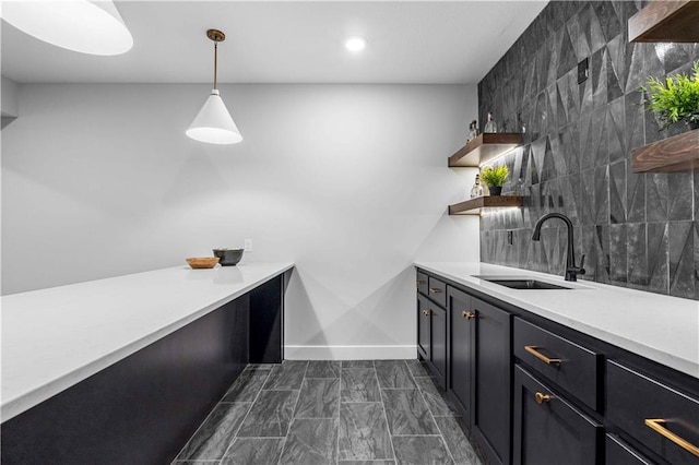 bar with a sink, baseboards, and hanging light fixtures