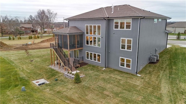 rear view of house with a lawn, central AC unit, stairs, and a sunroom