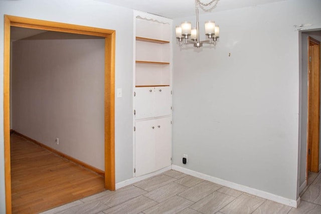 interior space featuring baseboards, light wood-style floors, and an inviting chandelier