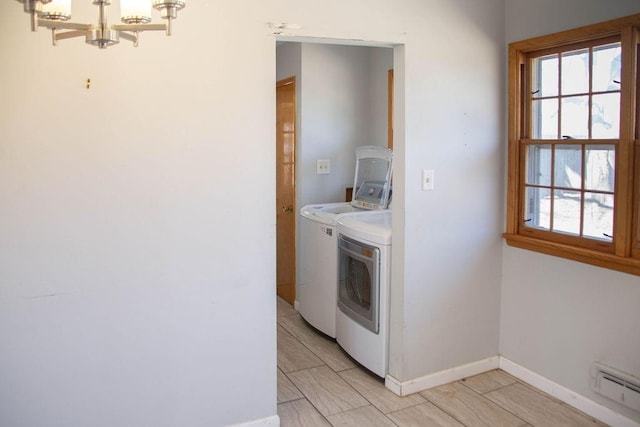 laundry room featuring baseboards, laundry area, washer and dryer, a notable chandelier, and a baseboard heating unit