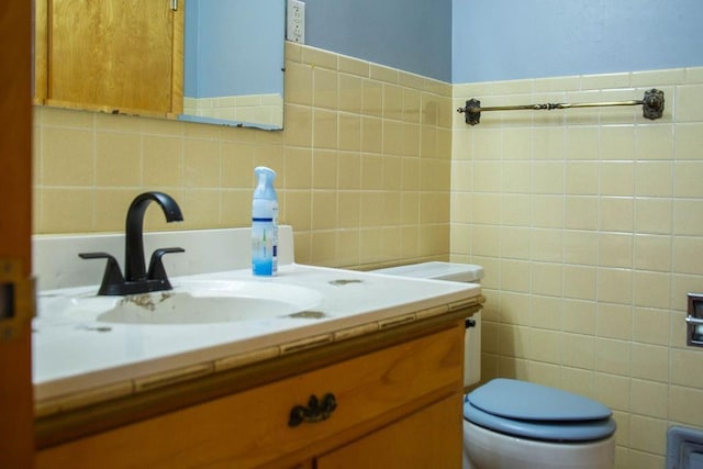 bathroom featuring vanity, tile walls, and toilet