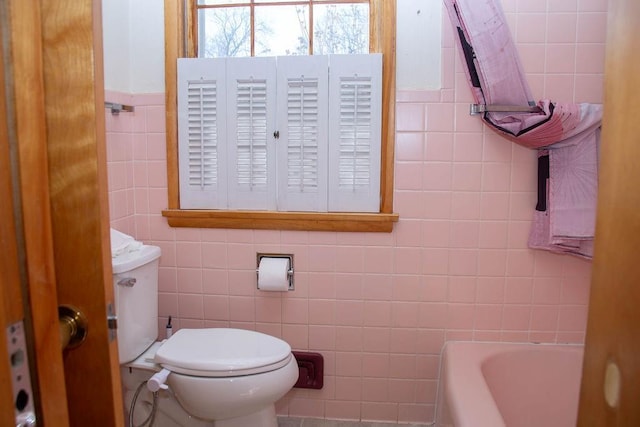 full bathroom with tile walls, toilet, and a bath