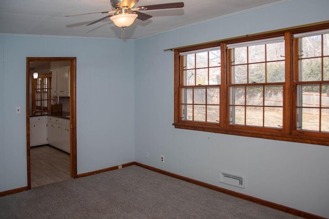 spare room featuring a wealth of natural light, visible vents, light colored carpet, and crown molding