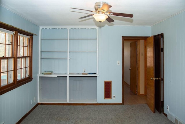 carpeted empty room with crown molding, visible vents, and ceiling fan