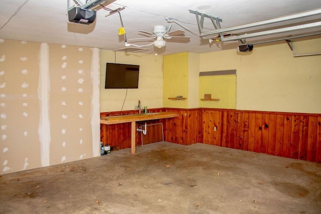 garage featuring a wainscoted wall, a garage door opener, and wood walls