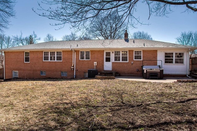 back of property featuring brick siding, entry steps, a lawn, a chimney, and a patio