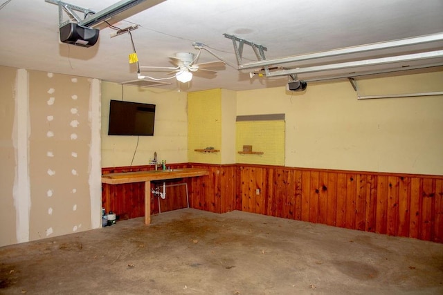 garage with a wainscoted wall, wood walls, and a garage door opener