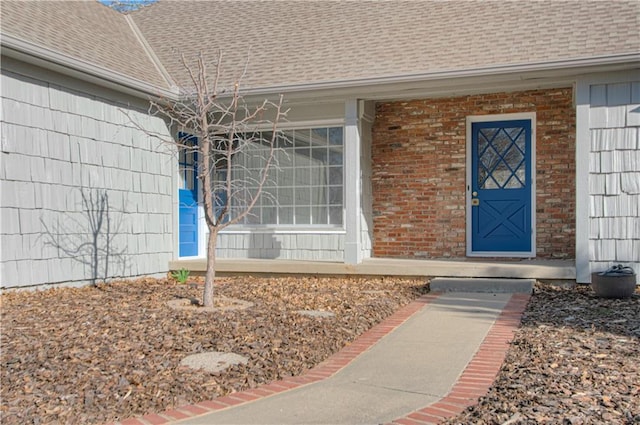 property entrance featuring brick siding and a shingled roof