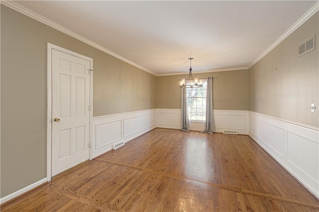 spare room featuring an inviting chandelier, wood finished floors, and visible vents