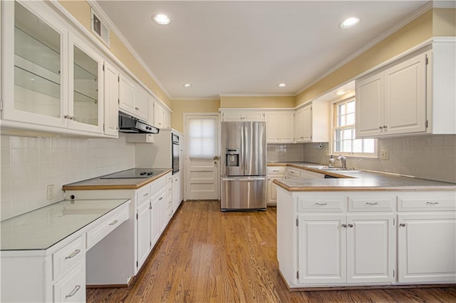 kitchen with black appliances, under cabinet range hood, a peninsula, white cabinetry, and a sink