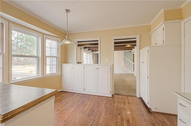 unfurnished dining area with light wood-style flooring, stairs, and ornamental molding