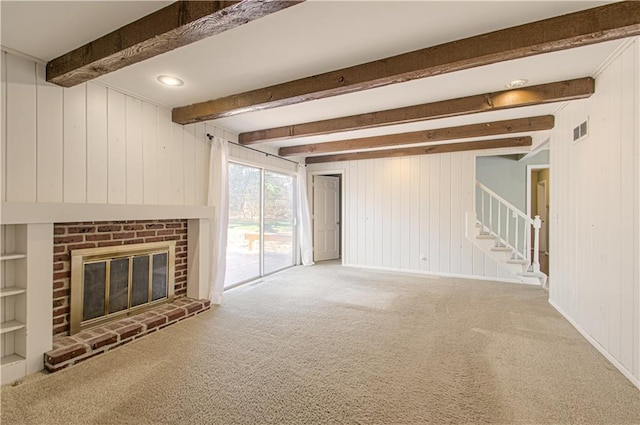 unfurnished living room with carpet, visible vents, beam ceiling, a fireplace, and stairs