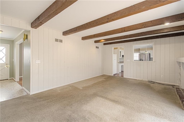 unfurnished living room with beamed ceiling, baseboards, visible vents, and carpet floors