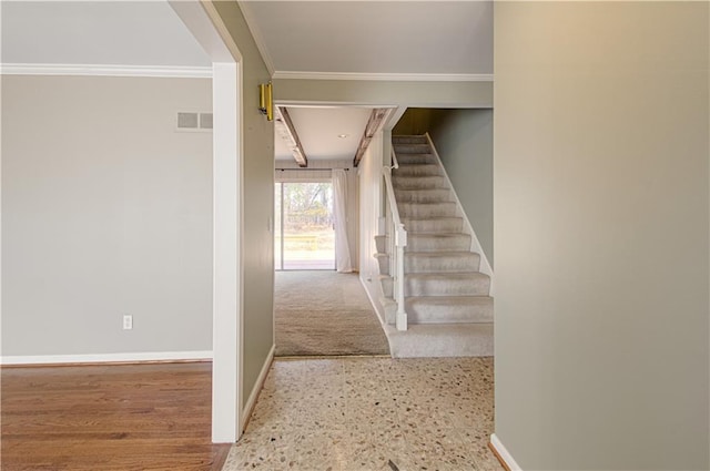 stairs with baseboards, visible vents, and ornamental molding