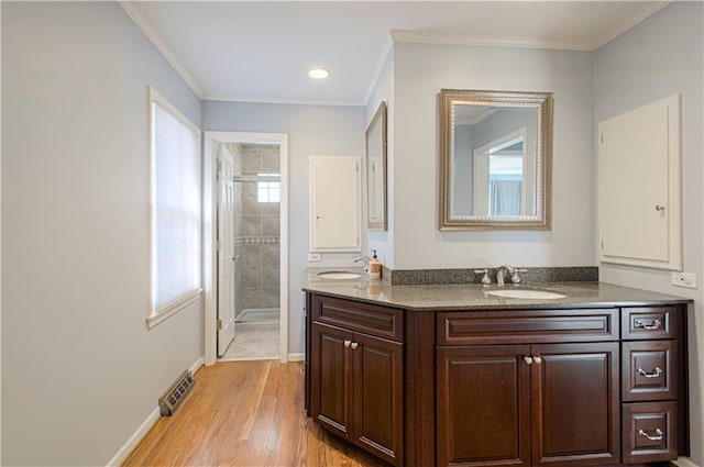 full bath featuring crown molding, tiled shower, visible vents, and a sink