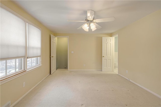 carpeted spare room featuring visible vents, baseboards, and a ceiling fan