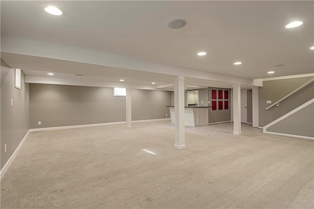 finished basement with stairway, recessed lighting, light colored carpet, and baseboards