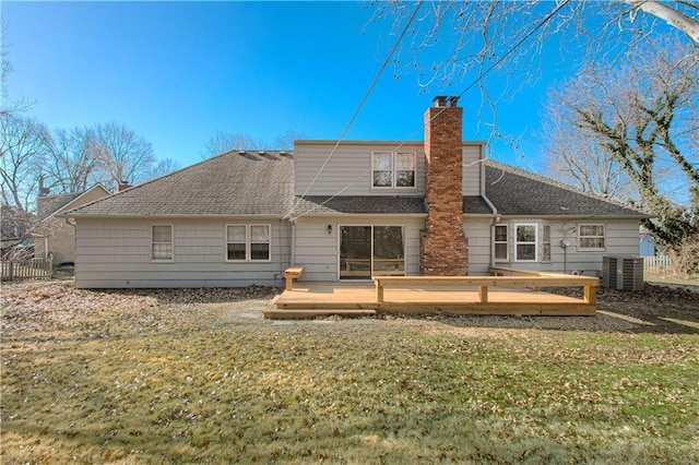 rear view of property with central AC unit, fence, a wooden deck, a chimney, and a lawn