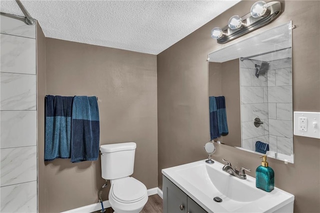 bathroom with vanity, baseboards, walk in shower, a textured ceiling, and toilet