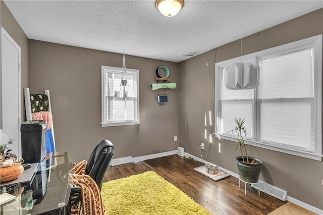 office space featuring visible vents, a textured ceiling, dark wood-type flooring, and baseboards