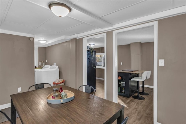 dining room with washing machine and clothes dryer, baseboards, and wood finished floors