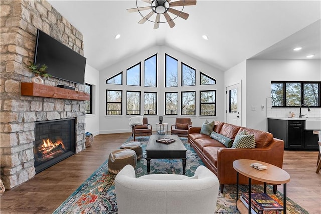 living room with light wood finished floors, a stone fireplace, and recessed lighting