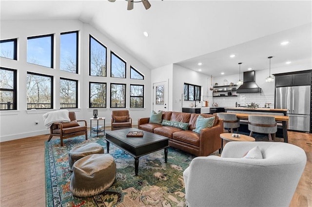 living area featuring baseboards, light wood finished floors, high vaulted ceiling, recessed lighting, and ceiling fan