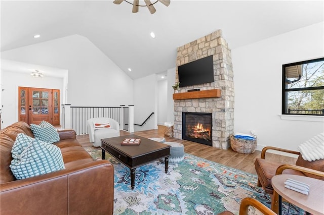 living area with a ceiling fan, wood finished floors, high vaulted ceiling, a fireplace, and recessed lighting