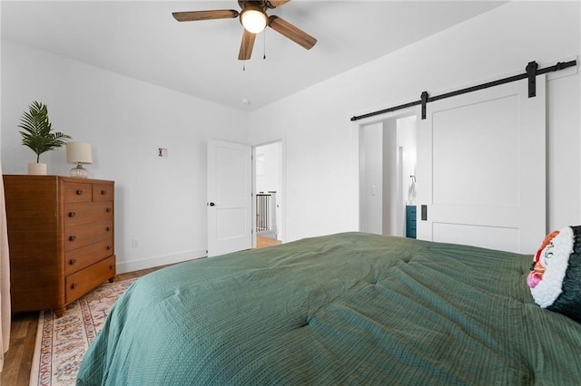 bedroom with a barn door, wood finished floors, and baseboards