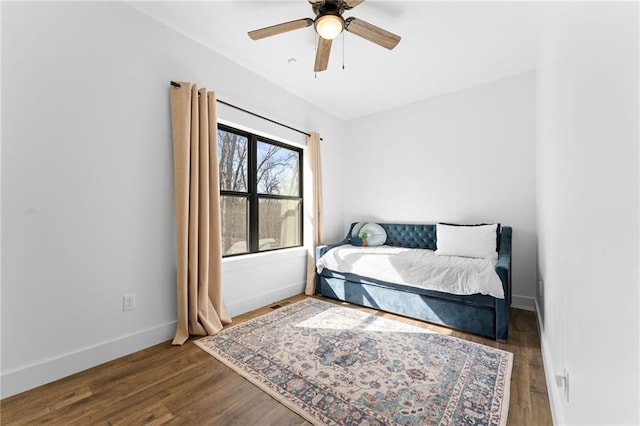 bedroom featuring baseboards, wood finished floors, and a ceiling fan