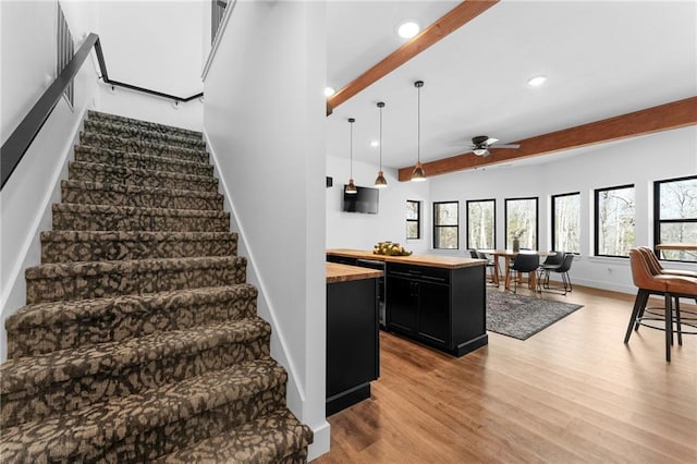 stairs with beam ceiling, recessed lighting, wood finished floors, and baseboards