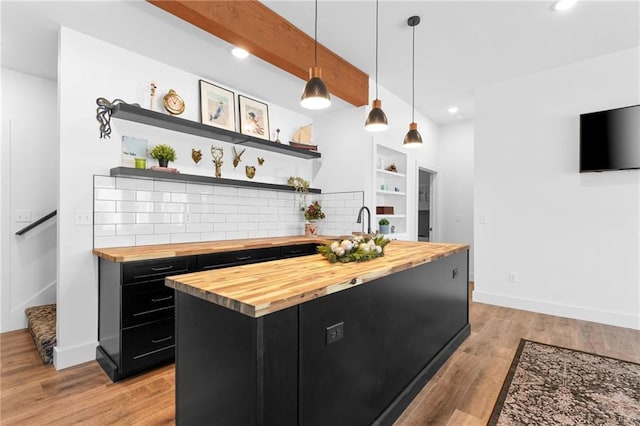 kitchen featuring open shelves, wooden counters, light wood-style floors, and dark cabinets