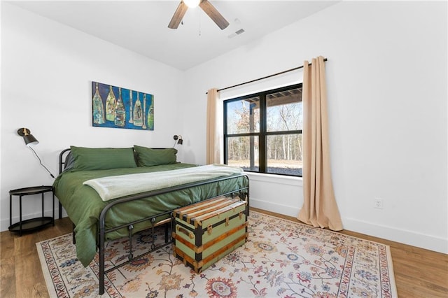 bedroom with visible vents, a ceiling fan, baseboards, and wood finished floors