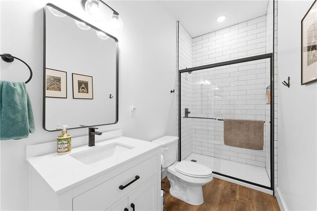 bathroom with vanity, a shower stall, toilet, and wood finished floors