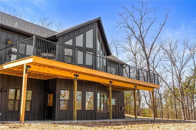 rear view of house featuring board and batten siding and a shingled roof