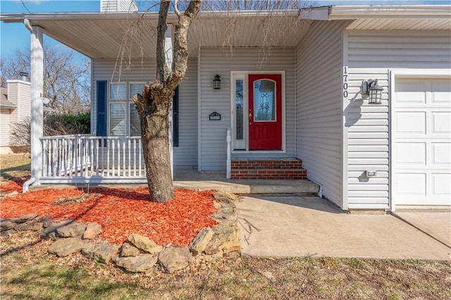 doorway to property with covered porch, an attached garage, and a chimney