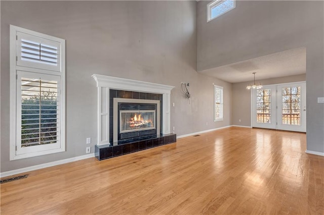 unfurnished living room with a wealth of natural light, wood finished floors, and a tiled fireplace