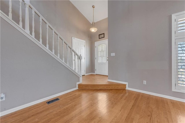 foyer featuring stairway, baseboards, wood finished floors, and a towering ceiling