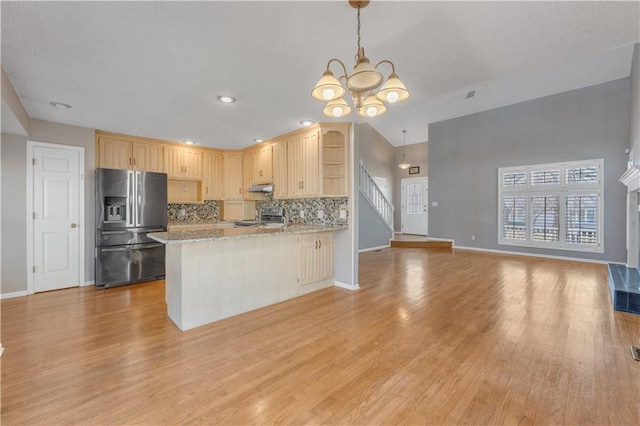 kitchen featuring light brown cabinets, a peninsula, open shelves, stainless steel appliances, and backsplash