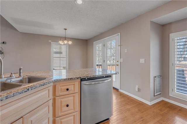 kitchen featuring light wood finished floors, baseboards, stainless steel dishwasher, a notable chandelier, and a sink