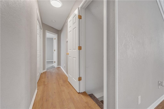 hall with baseboards and light wood-style floors